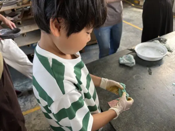 りょうちゃん
ぼくはコースターを使った時、苦労したことが何個かありました。
1つ目は、金属に、ぬかをぬる時のぬかの厚さの加減です。ぬかは厚過ぎでもダメだし薄すぎてもだめだから苦戦しました。
2つ目は火で炙ることです。火をつけるための棒は重たくてとても大変でした。
3つ目は着色をする時です。アンモニアガスの匂いがキツく目に染みたので大変でした。
　このように銅器の仕事をしておられる方がたの皆さんは、苦労をして頑張っているのが分かりました。
　この日はとても楽しかったのでまたコースターを苦戦や苦労をして作りたいと思いました。
