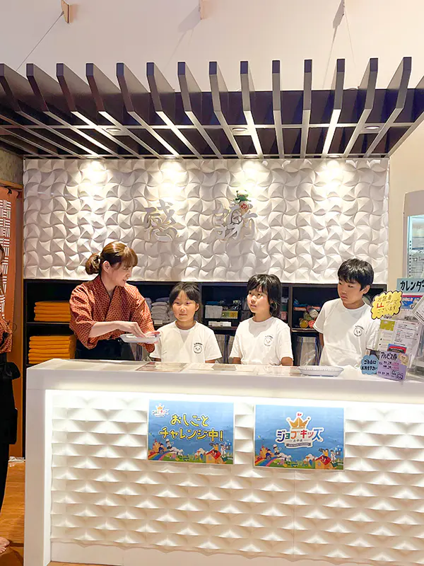 もったん
接客では、始めは恥ずかしくてなかなか声が出なかったけど、最後にはお客さんに挨拶をすることができて、すっきりしました。バックヤードでは、お風呂の湯加減を調整する場所でとても蒸し暑かったです。そこで働く職員の方は大変そうだと思いました。シャンプーの詰め替えのとき、濃いボトルの色だと詰め替えの量が分かりにくくて少しドキドキしたけど、入れることができて嬉しかったです。ソフトクリーム作りは、落としたりしないか心配だったけど、きれいに作れたので良かったです。